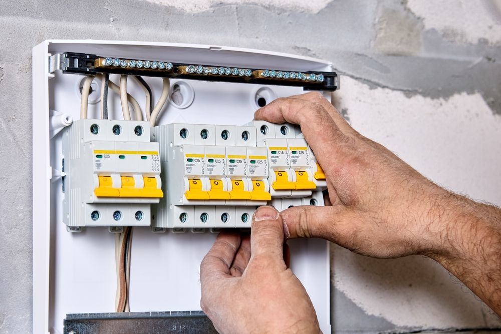 Hands Installing Circuit Breakers in an Electrical Panel, With Wires and a Neutral Bar — CDT Electrical in Lennox Head, NSW