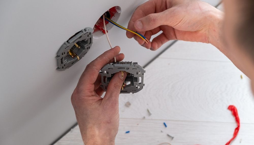 Person Installing Electrical Wiring Into a Gray Outlet Box on a White Wall — CDT Electrical in Ballina, NSW
