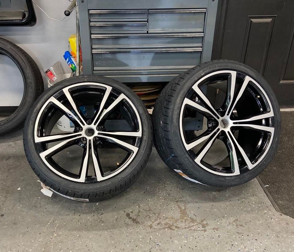 A pair of black and white wheels and tires on a garage floor.