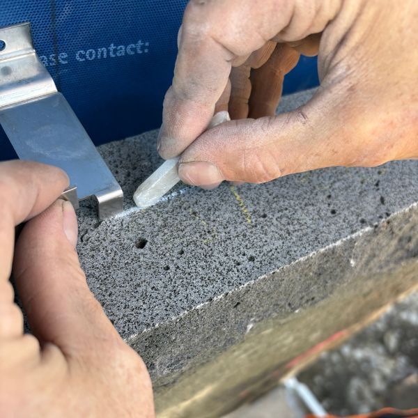 Hands installing a stone clip into natural stone veneer
