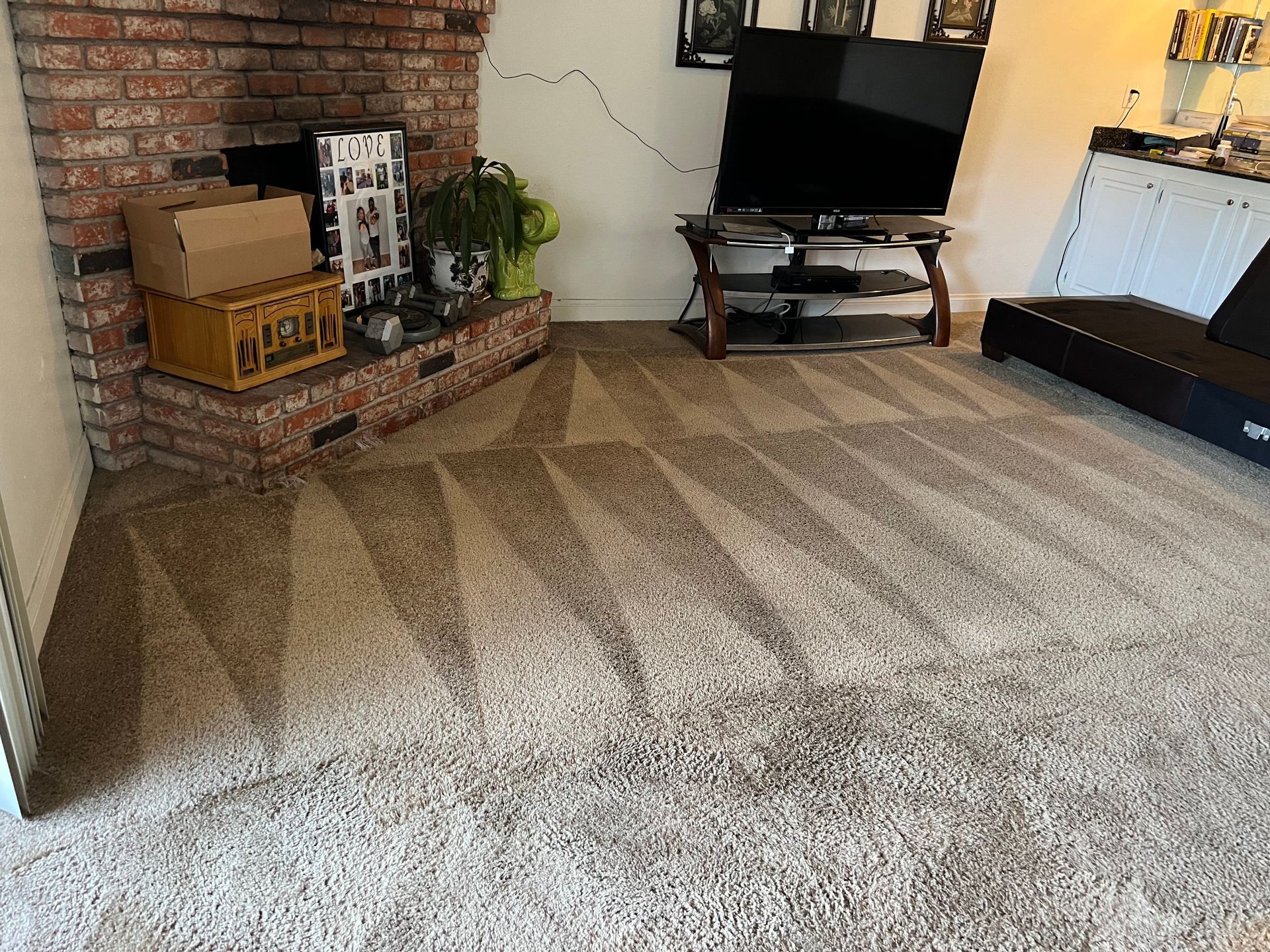 Living room with brick fireplace, TV, and carpet with a geometric pattern.