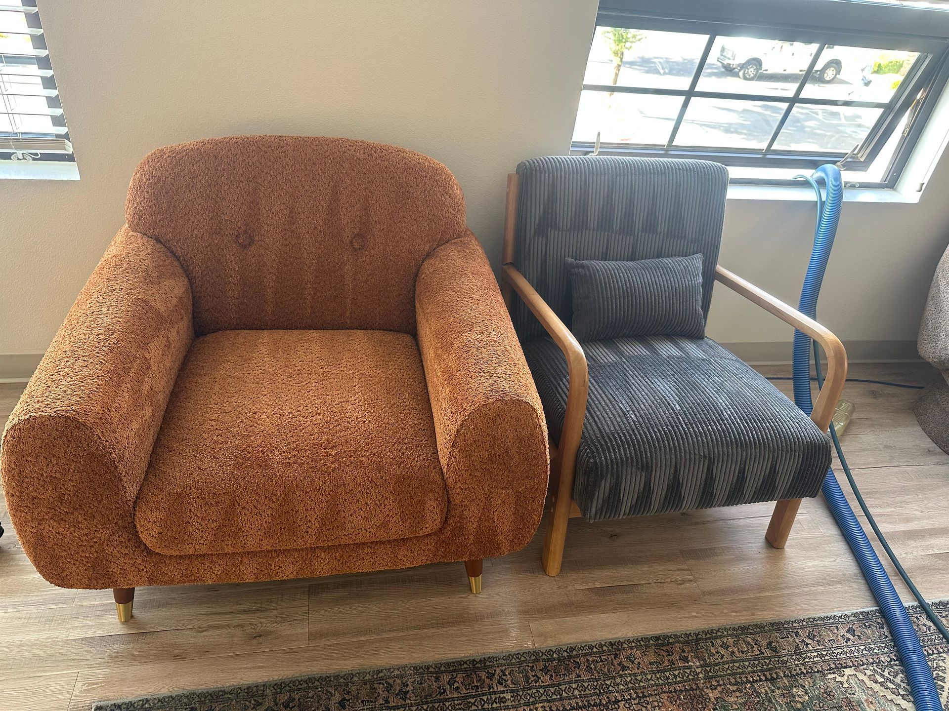 Two armchairs: one orange patterned, the other gray patterned with wooden arms.