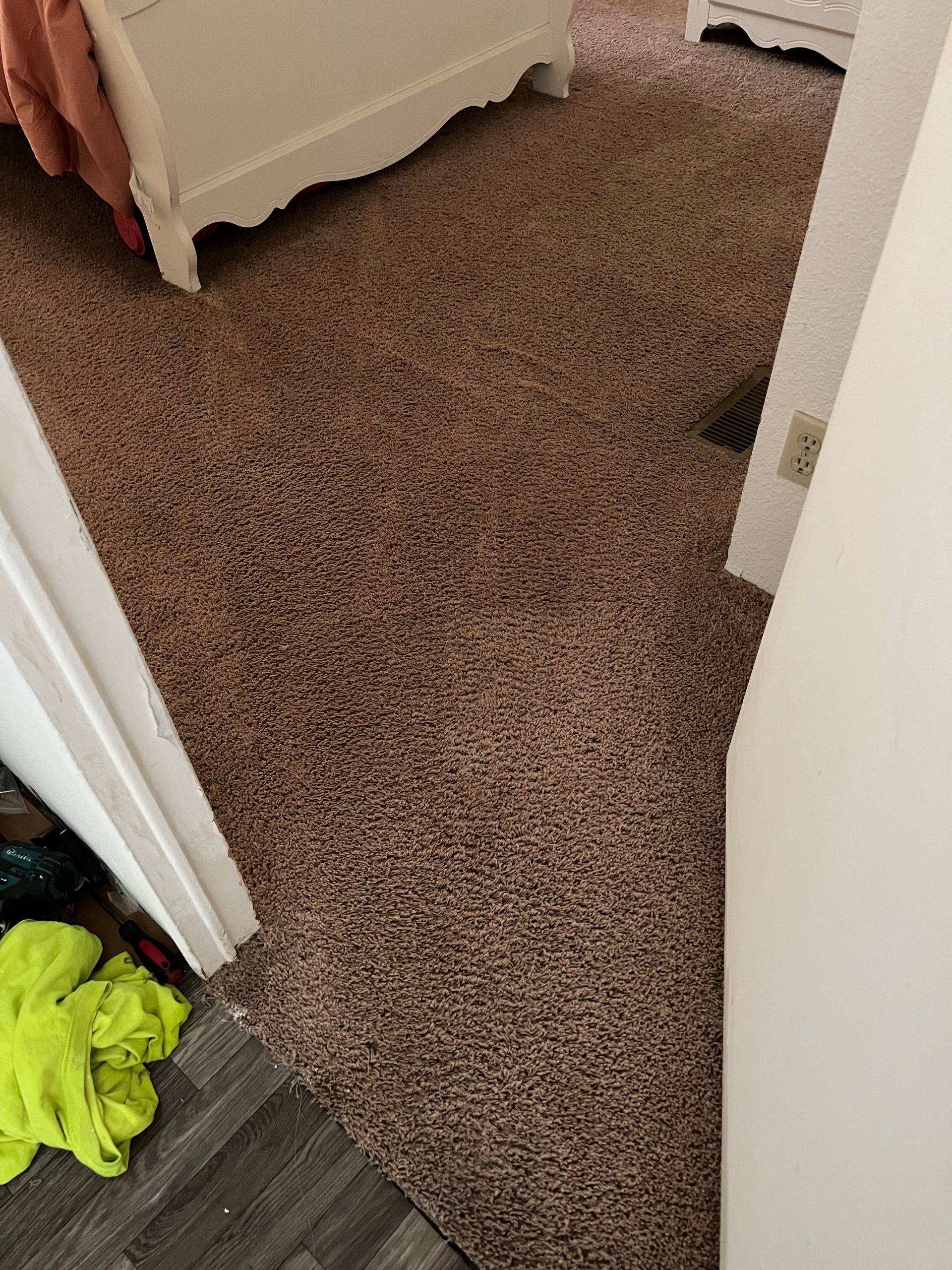 Brown carpeted floor in a room, visible from a doorway, with a white cabinet and door frame.