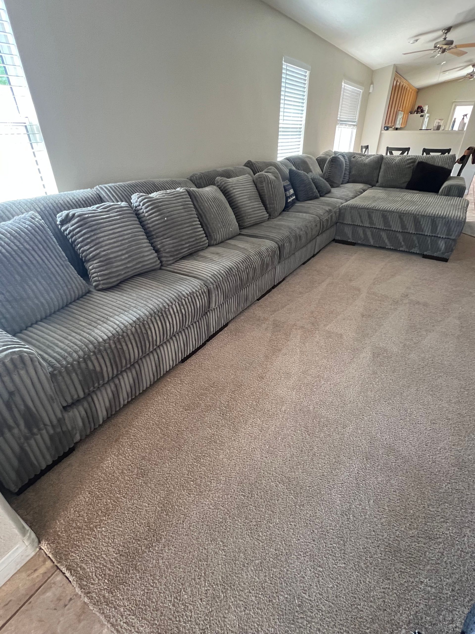 Large gray sectional sofa on a light brown carpet in a well-lit living room.