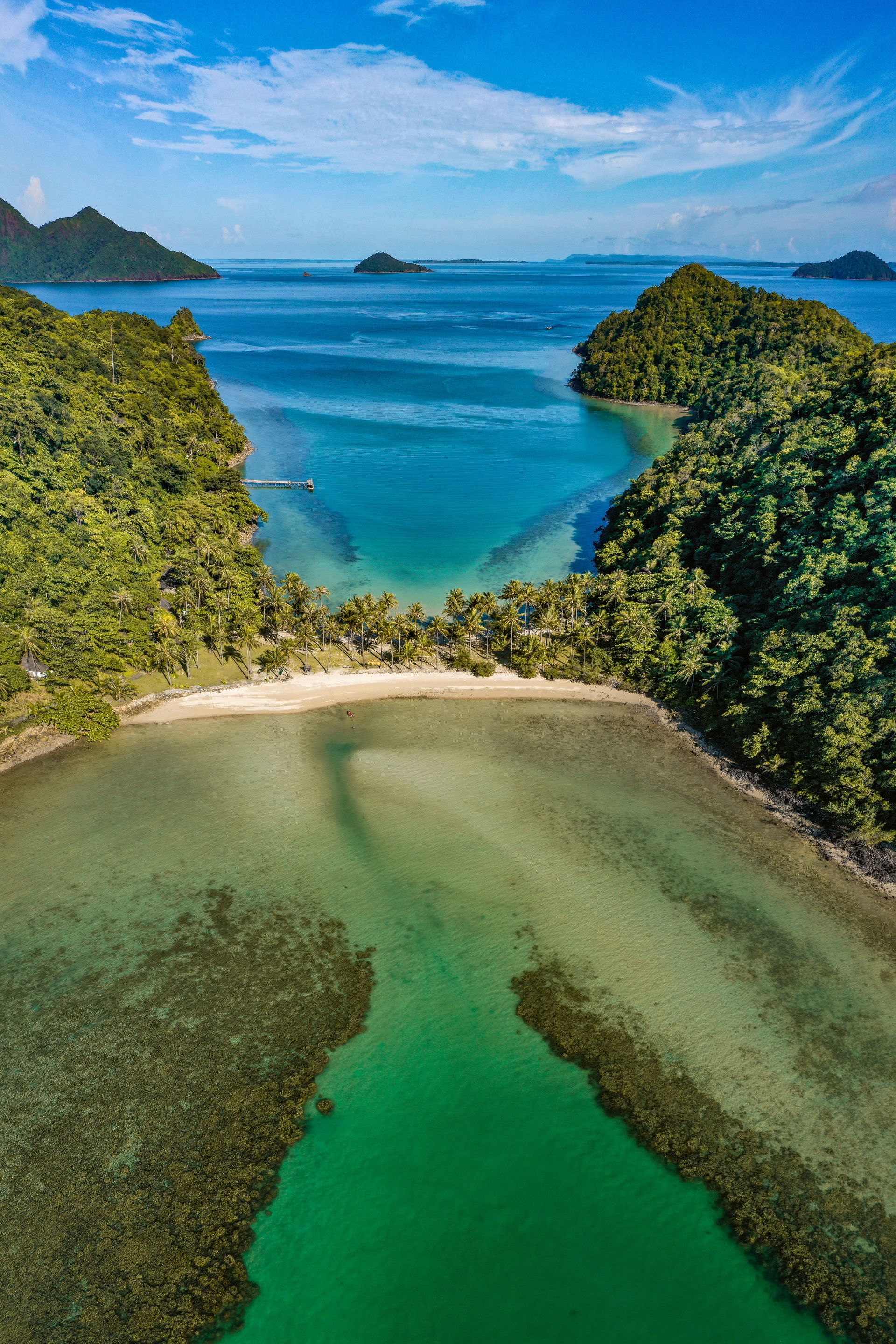 An aerial view of a small island in the middle of the ocean surrounded by trees.