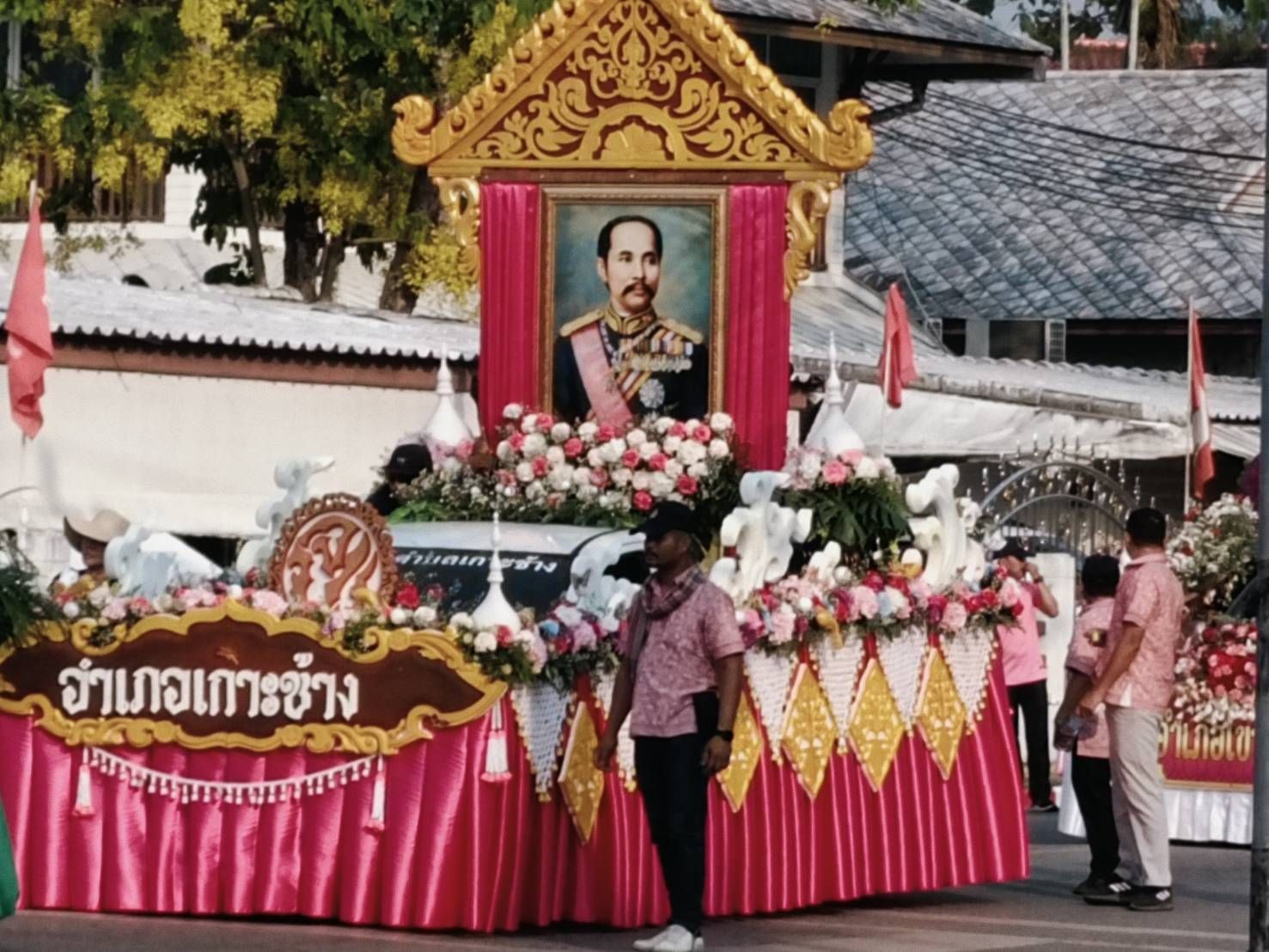 A man stands in front of a display of flowers and a picture of a man