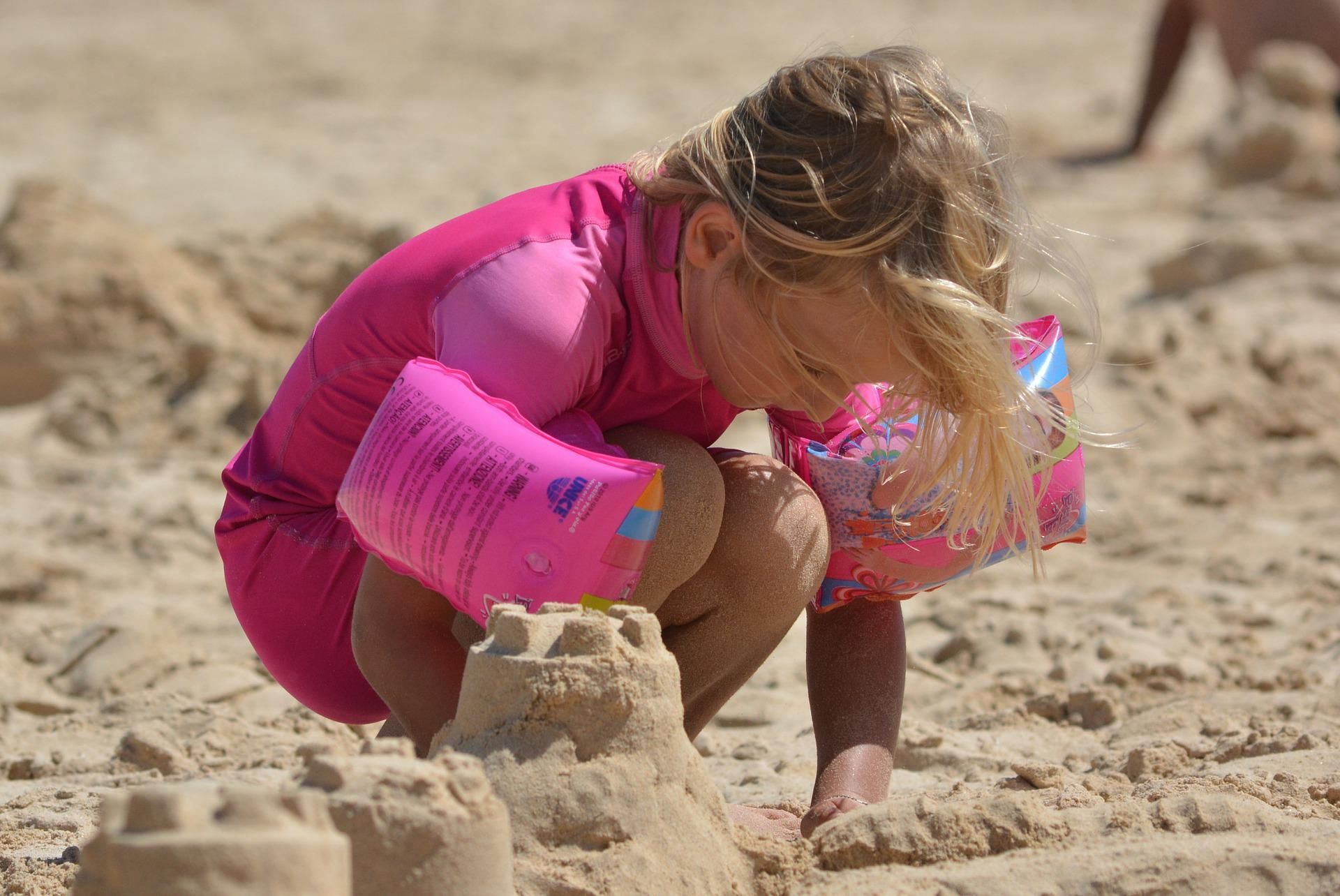 Een klein meisje speelt in het zand op het strand.