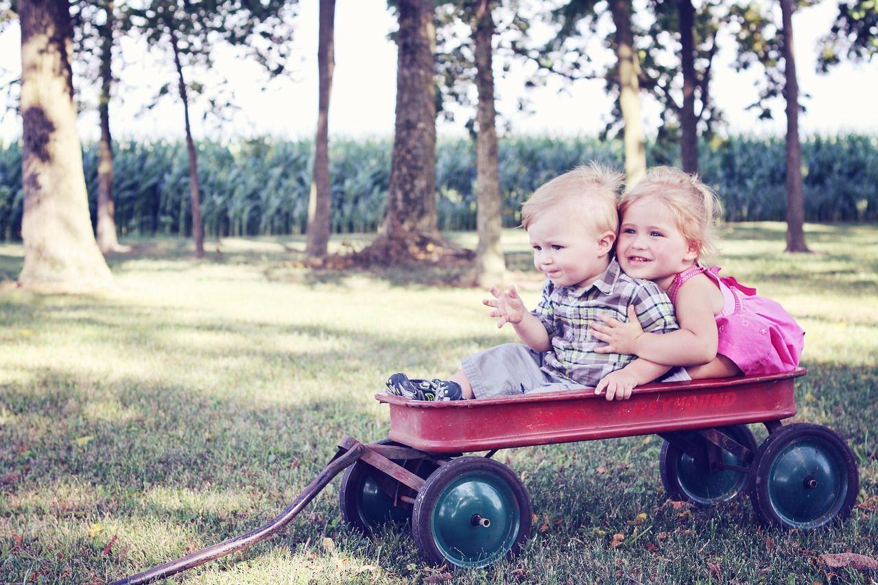 Een jongen en een meisje zitten in een rode wagen.