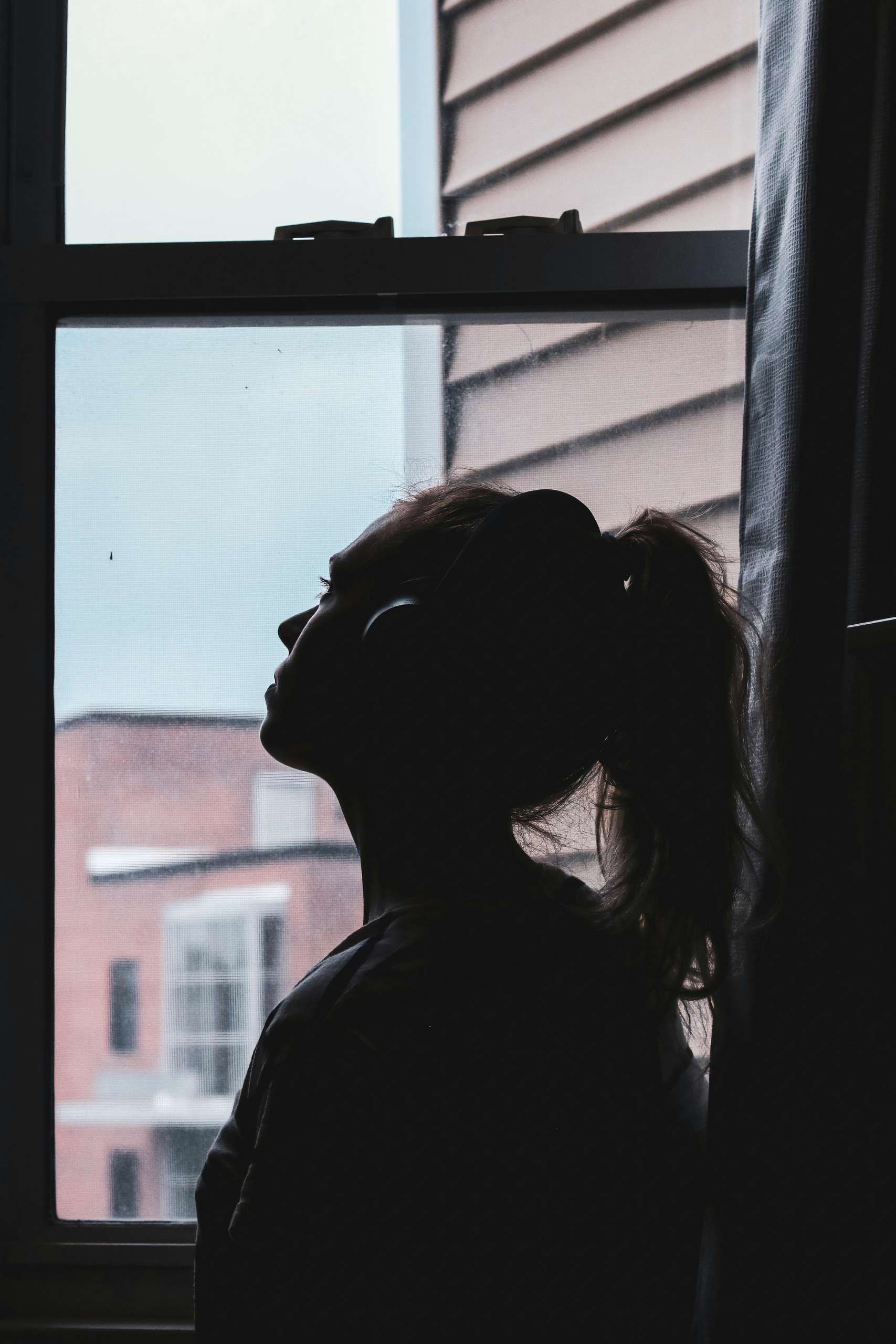 a silhouette of a woman staring out the window