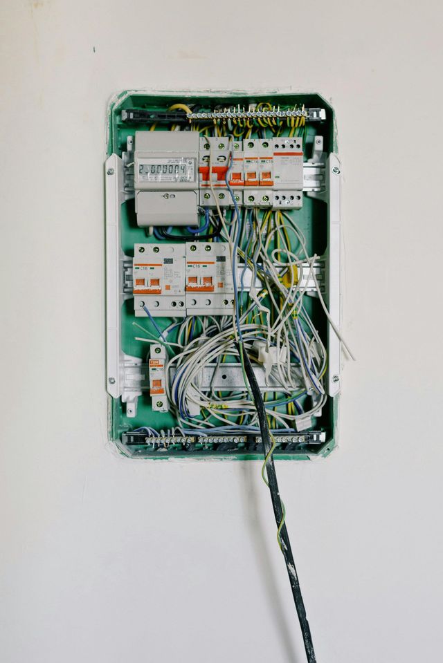 Open electrical circuit breaker panel with exposed wires and switches in a wall recess