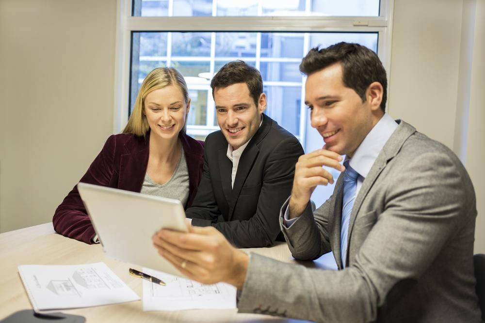A Group of People Are Sitting at A Table Looking at A Tablet — Twin Peaks Finance In Helensvale, QLD