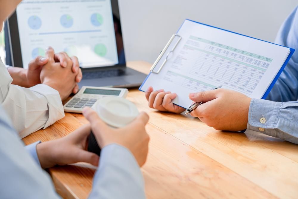 A Group of People Are Sitting at A Table Looking at A Clipboard — Twin Peaks Finance In Helensvale, QLD