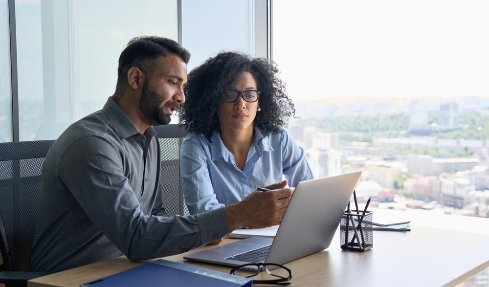 A Man and A Woman Are Sitting at A Table Looking at A Laptop Computer — Twin Peaks Finance In Helensvale, QLD