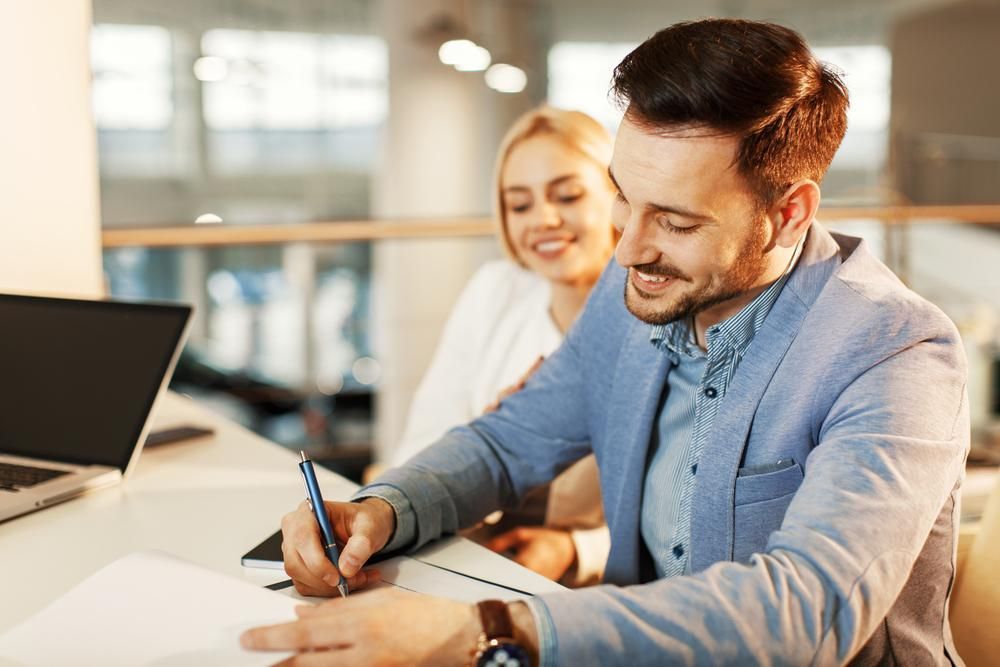 A Man Is Writing on A Piece of Paper While a Woman Looks on — Twin Peaks Finance In Helensvale, QLD
