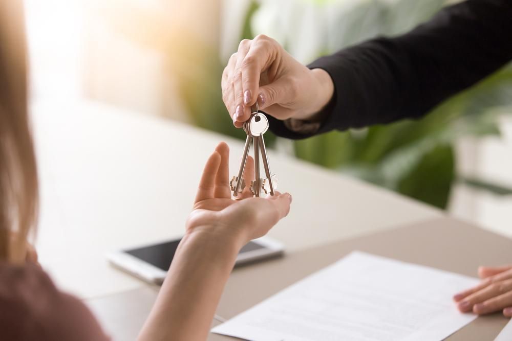 A Woman Is Getting Keys from A Real Estate Agent — Twin Peaks Finance In Helensvale, QLD