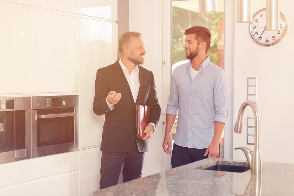 Two Men Are Standing in A Kitchen Talking to Each Other — Twin Peaks Finance In Helensvale, QLD