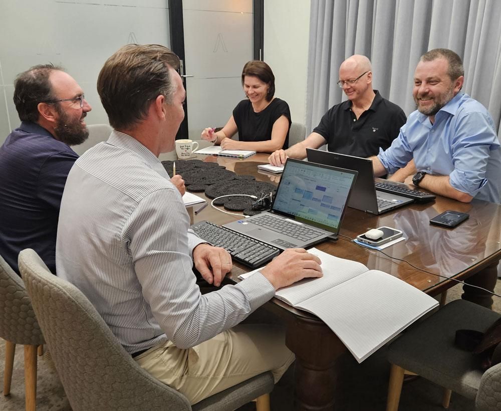 A Group of People Are Sitting Around a Table with Laptops — Twin Peaks Finance In Helensvale, QLD