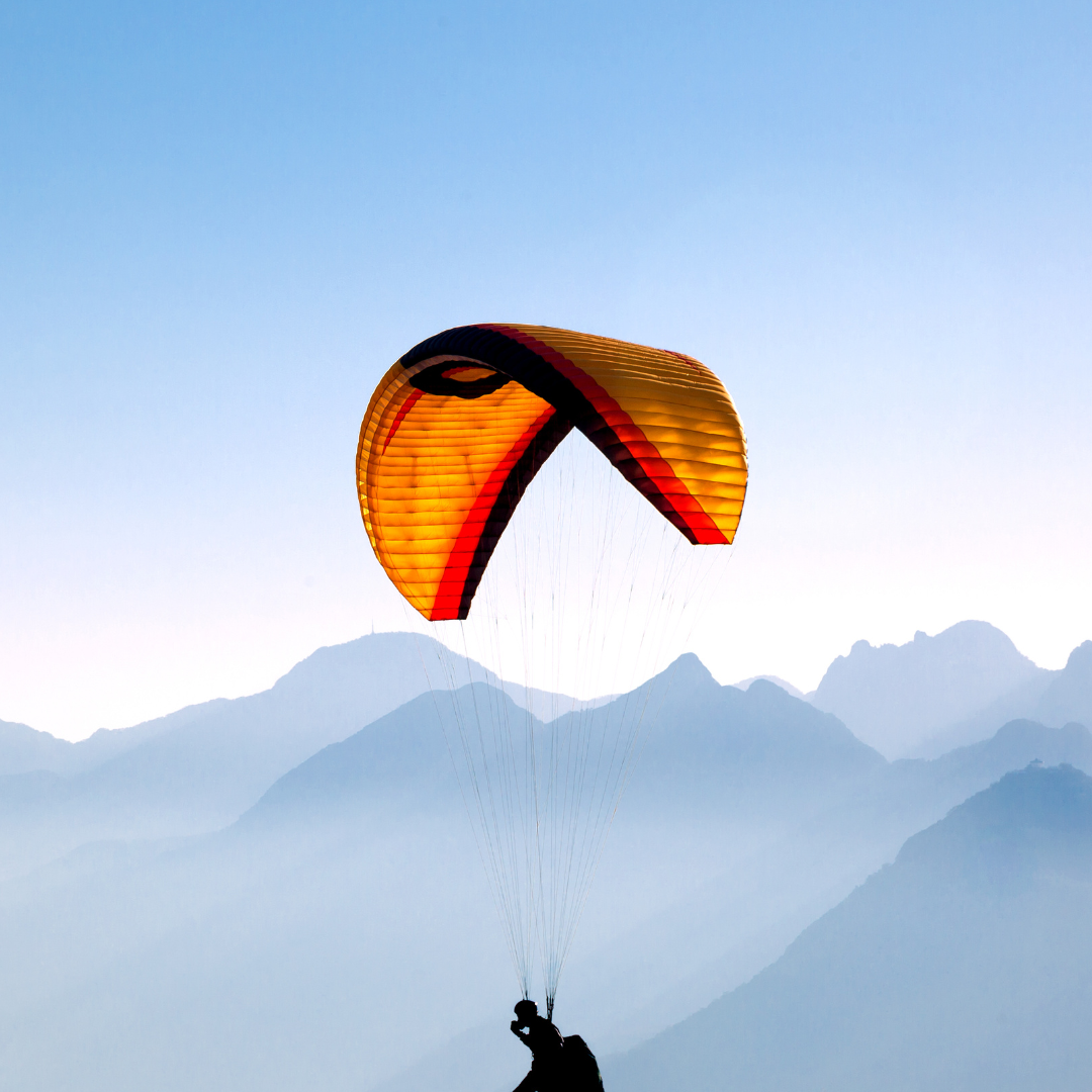 Eine Person fliegt mit einem Fallschirm über Berge
