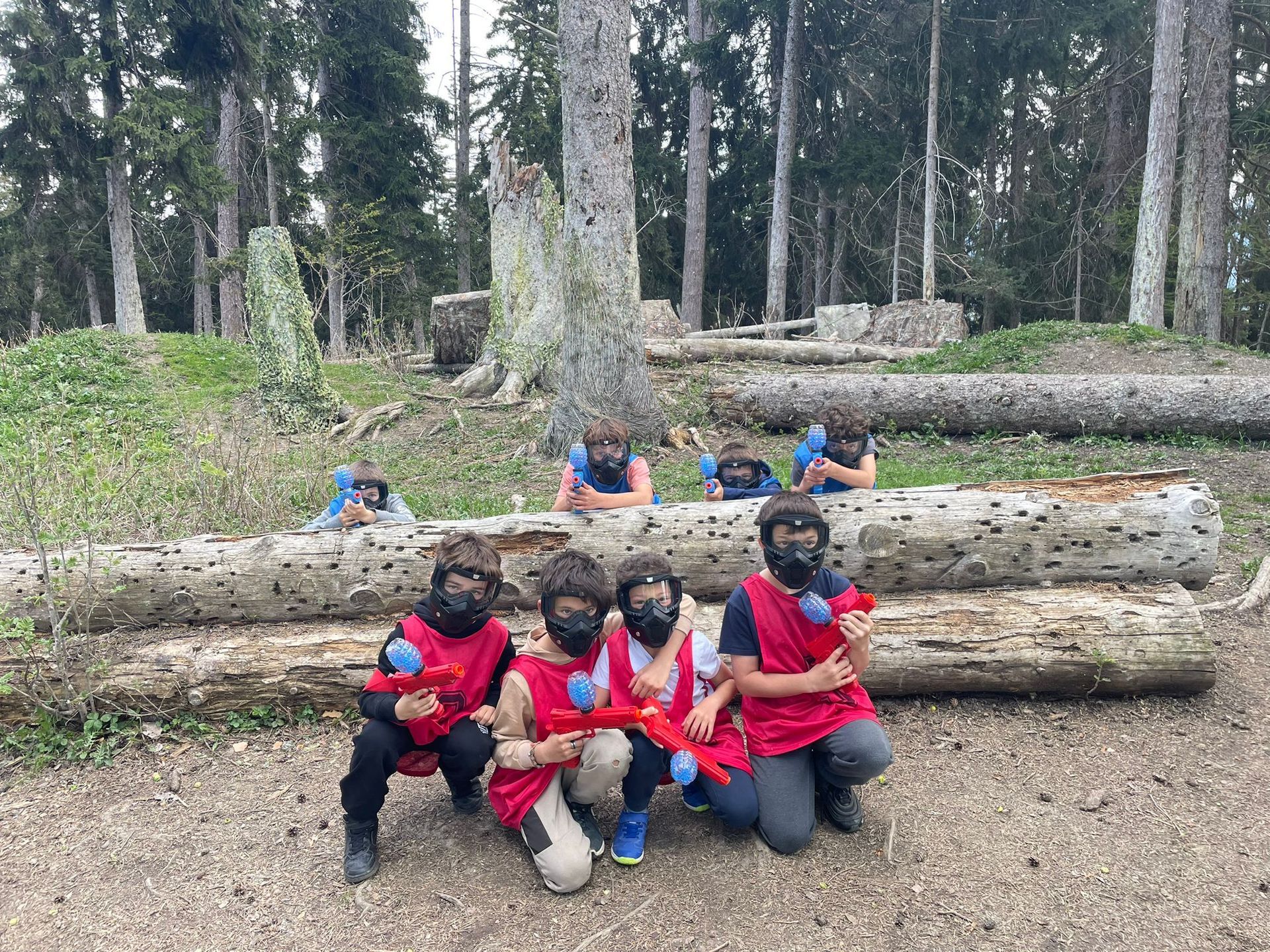 Un groupe d'enfants joue au paintball dans les bois et pose pour une photo.