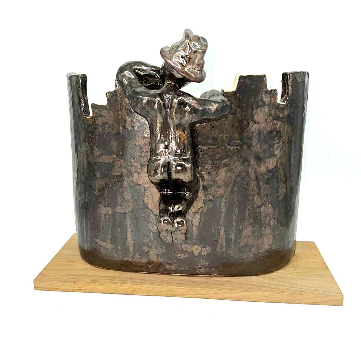Roestig metalen beeld met een gekroond gezicht op een houten sokkel