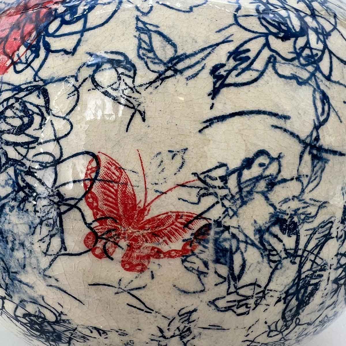 Witte keramische kom met blauwe bloemmotieven en een rood vlinderontwerp.