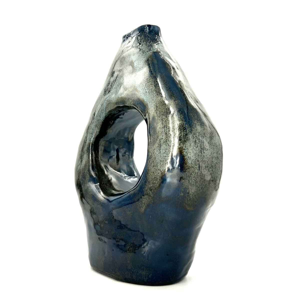 Abstracte metalen sculptuur met een holle opening, in donkerzilveren en zwarte tinten.