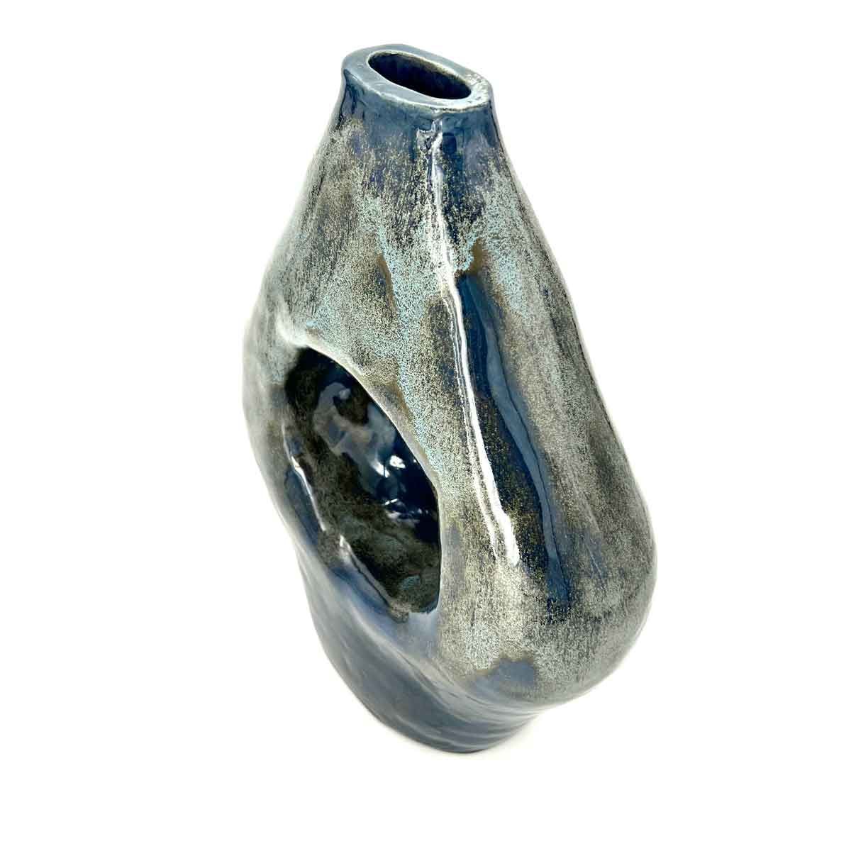 Blauwgrijze keramische vaas met een asymmetrisch, gestructureerd oppervlak en een open ovale opening.