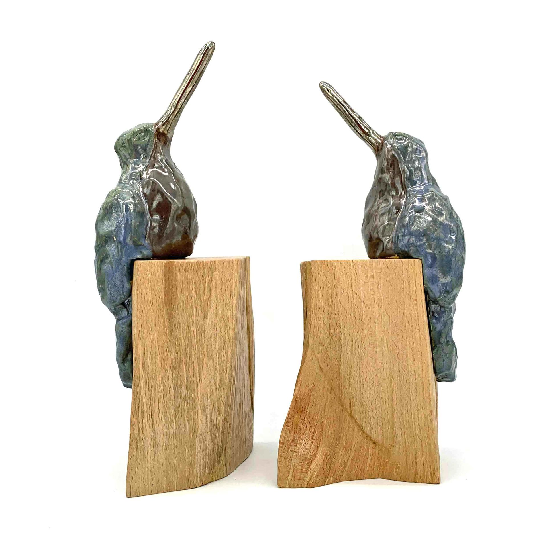 Twee kleine abstracte sculpturen van metaal en hout staan ​​tegenover elkaar op een witte achtergrond.