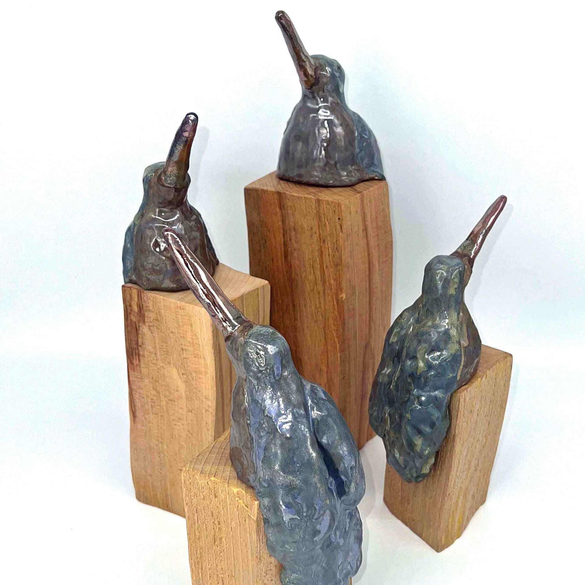 Vier abstracte metalen sculpturen met houten blokken op een witte achtergrond.
