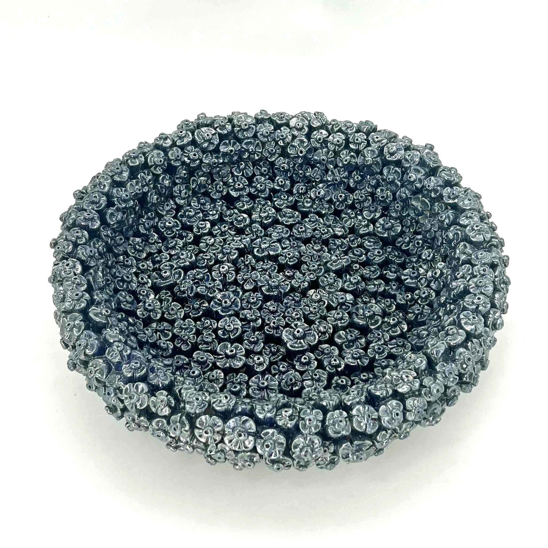 Rond, blauwgrijs, getextureerd schuursponsje op een witte achtergrond.