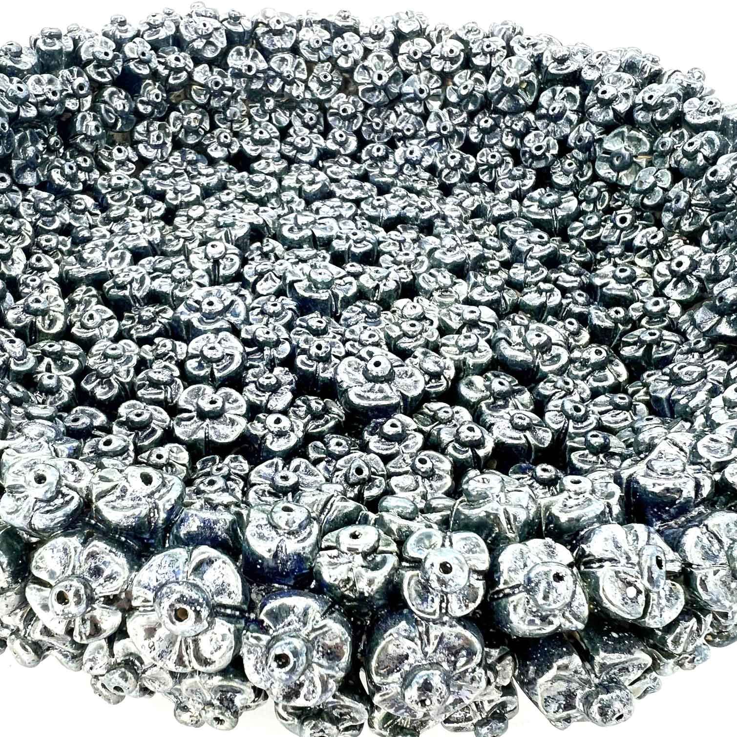 Een stapel glanzende, zilverkleurige metalen kralen of korrels, dicht op elkaar gepakt, van dichtbij bekeken.