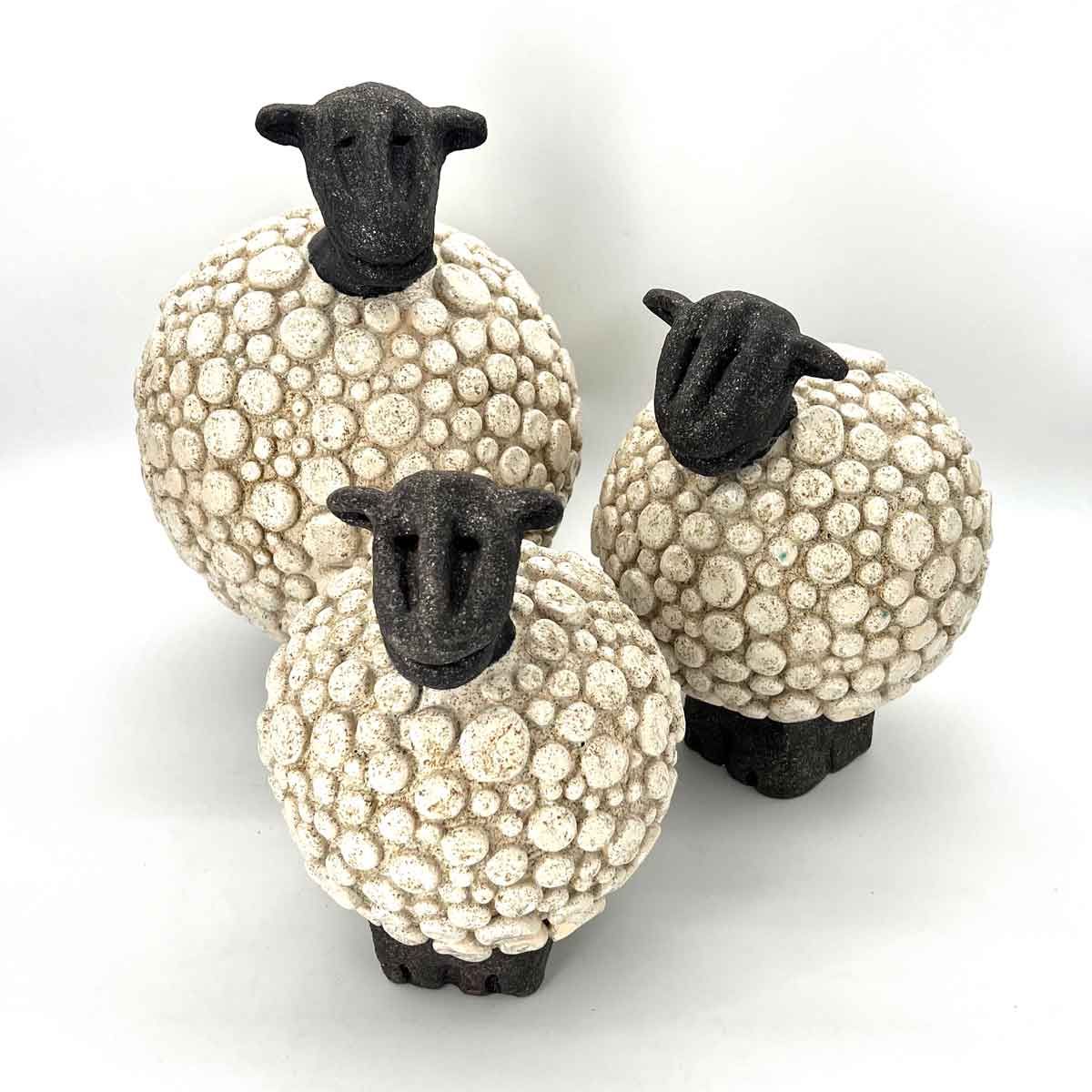 Drie kleine schaapjesfiguurtjes met witte, gestructureerde lijfjes en zwarte kopjes op een witte achtergrond.