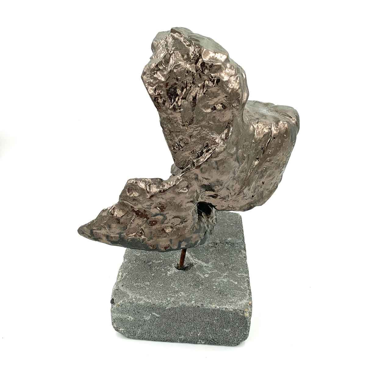 Abstracte bronzen sculptuur op een stenen sokkel, met gebogen en gestructureerde vormen.