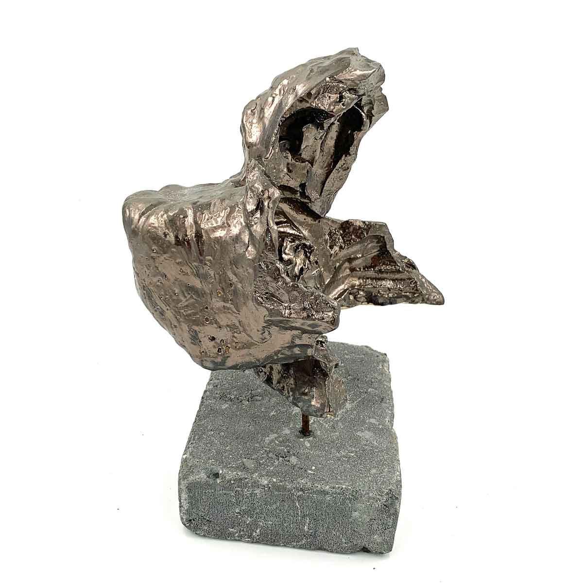 Abstracte metalen sculptuur op een grijze sokkel, die lijkt op een vogel of wezen met een open bek.