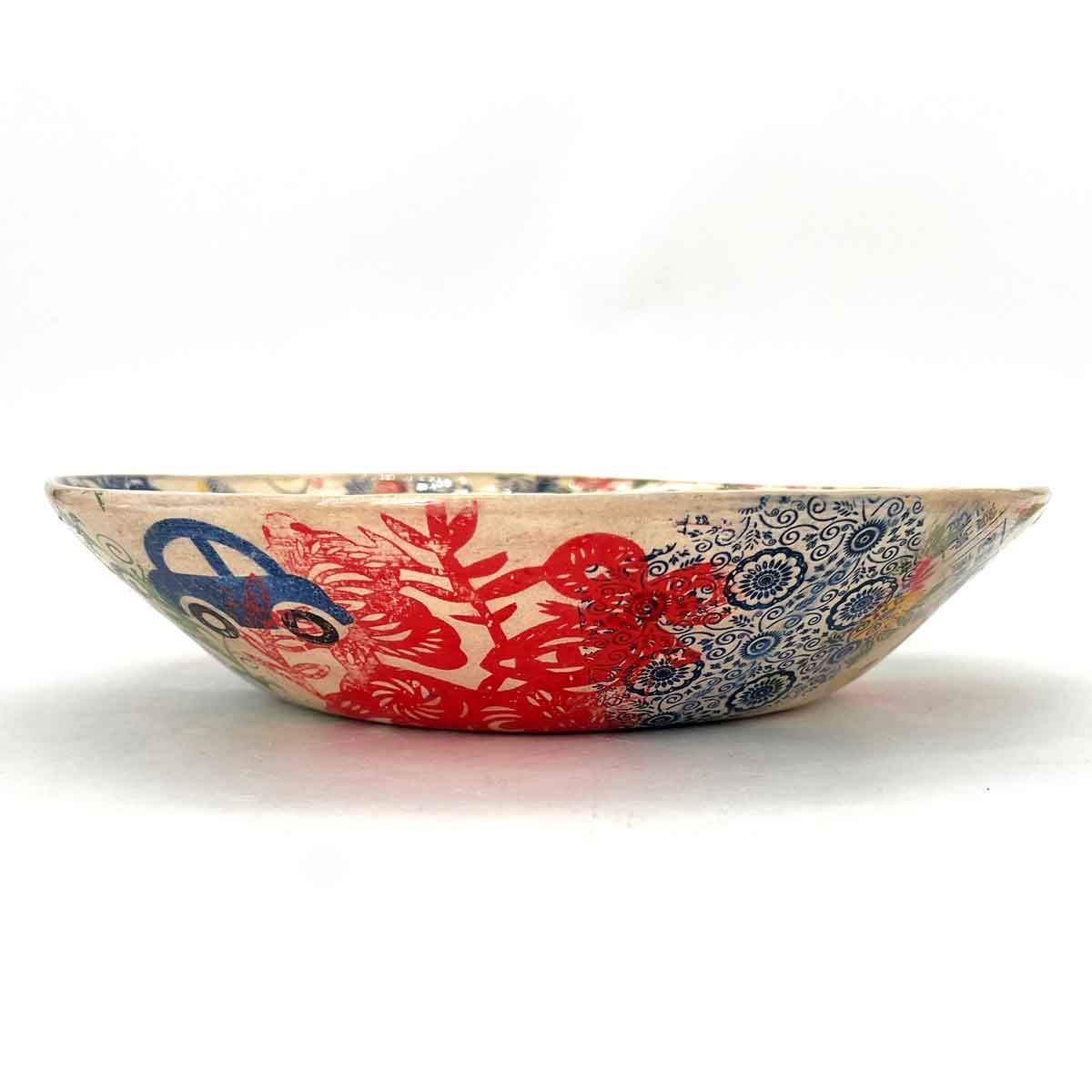 Ondiepe keramische kom met een blauw en rood bloemenpatroon op een witte achtergrond.
