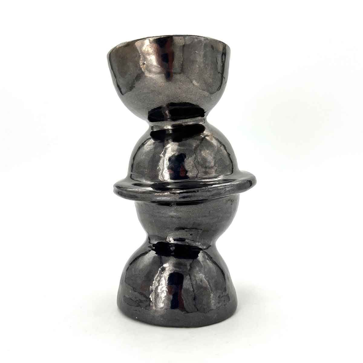 Verchroomd, dubbelzijdig metalen object in kelkvorm met een uitlopende rand en een afgerond middenstuk op een witte achtergrond.