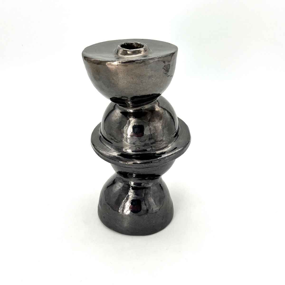 Glanzend zilverkleurig metalen schaakstuk, waarschijnlijk een toren, op een witte achtergrond.