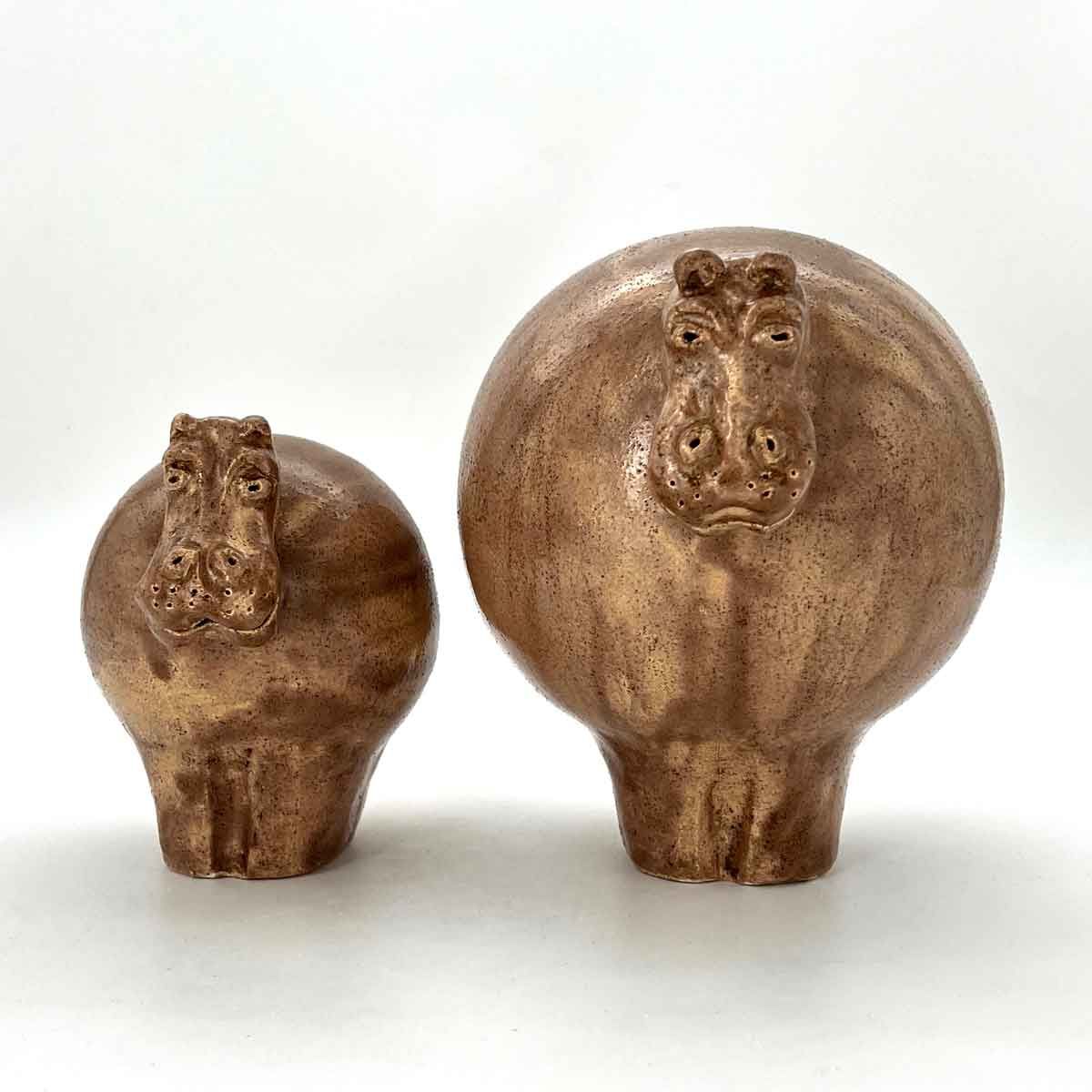 Twee bronzen nijlpaardbeeldjes, een groter en een kleiner, op een witte achtergrond.