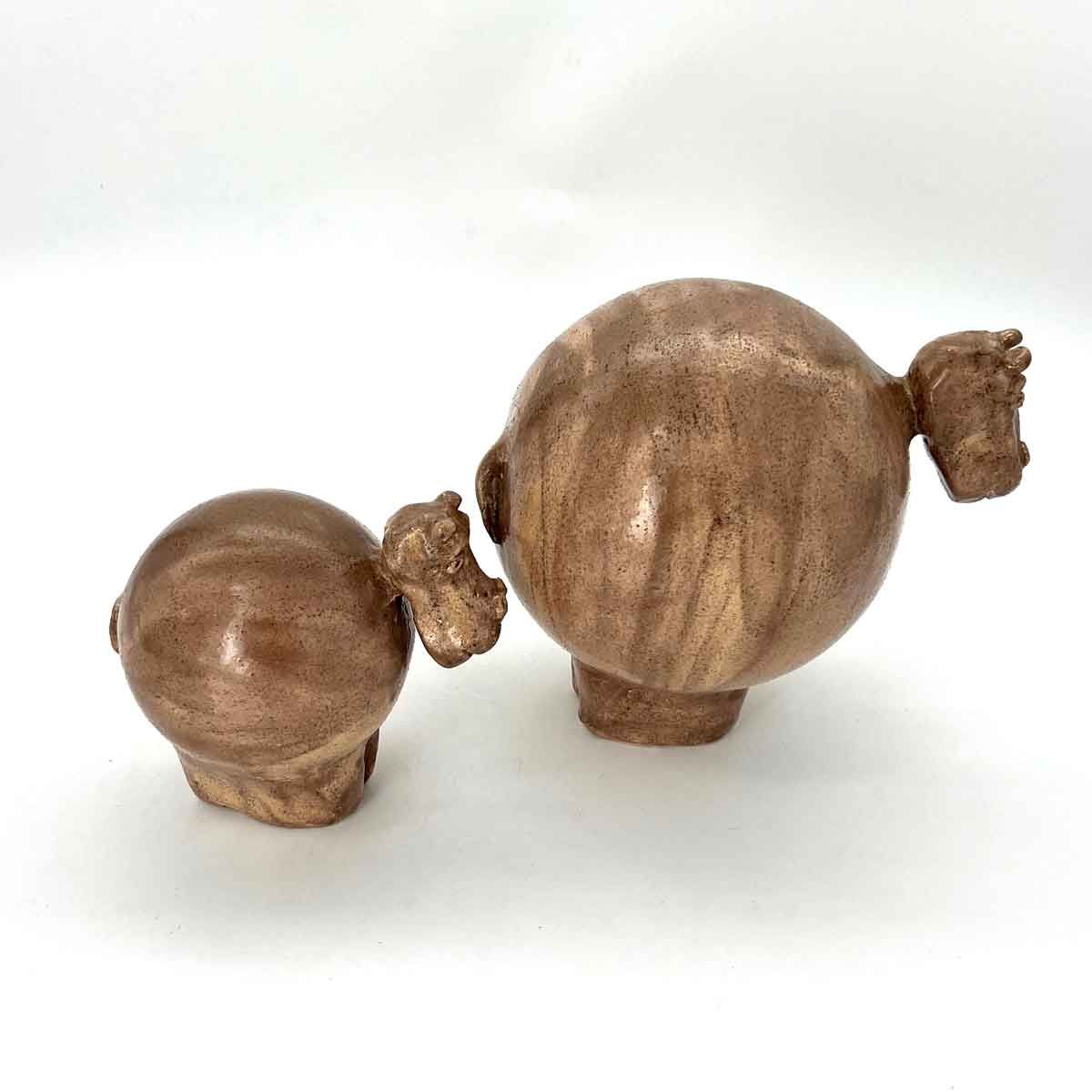 Twee kleine bruine, gesneden houten beeldjes op een witte achtergrond.