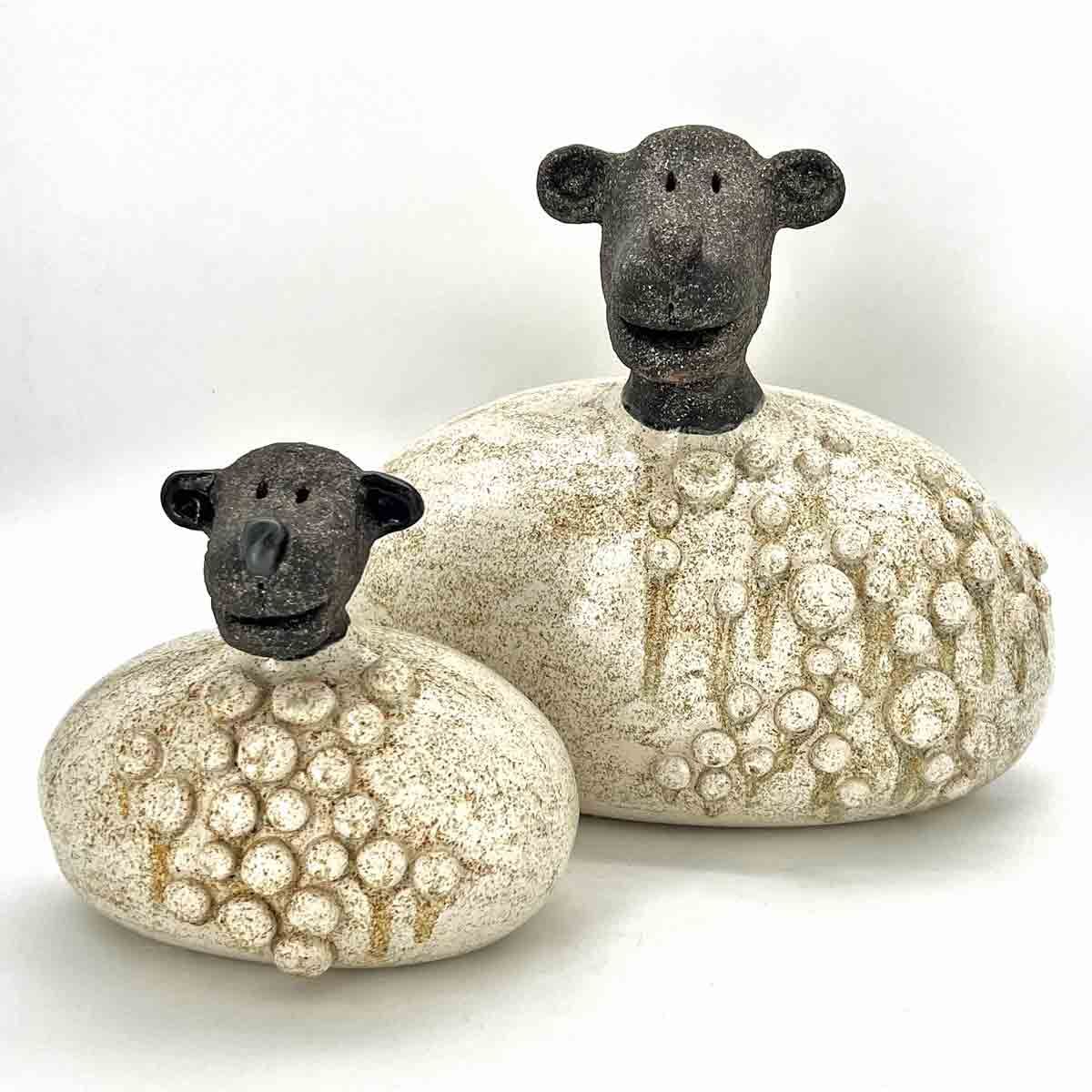 Twee kleine schaapjes met donkere kopjes en crèmekleurige, gestreepte lijfjes op een witte achtergrond.