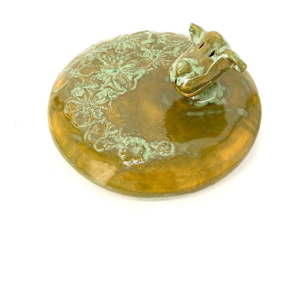 Bronzen kikkerfiguurtje met een groene patina op een ronde amberkleurige voet.