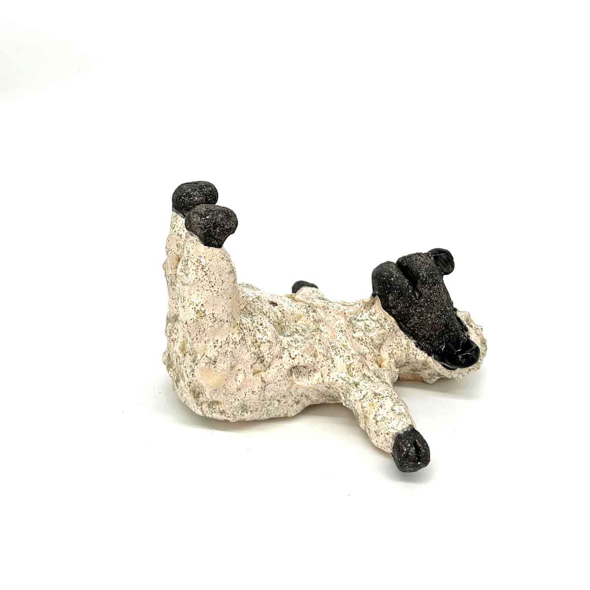 Klein beige beeldje met zwarte accenten, dat op een hond of ander dier lijkt, op een witte achtergrond.