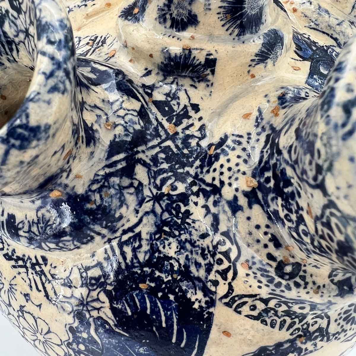 Blauw-wit gestreepte keramische kom met een ingewikkeld bloemenpatroon.