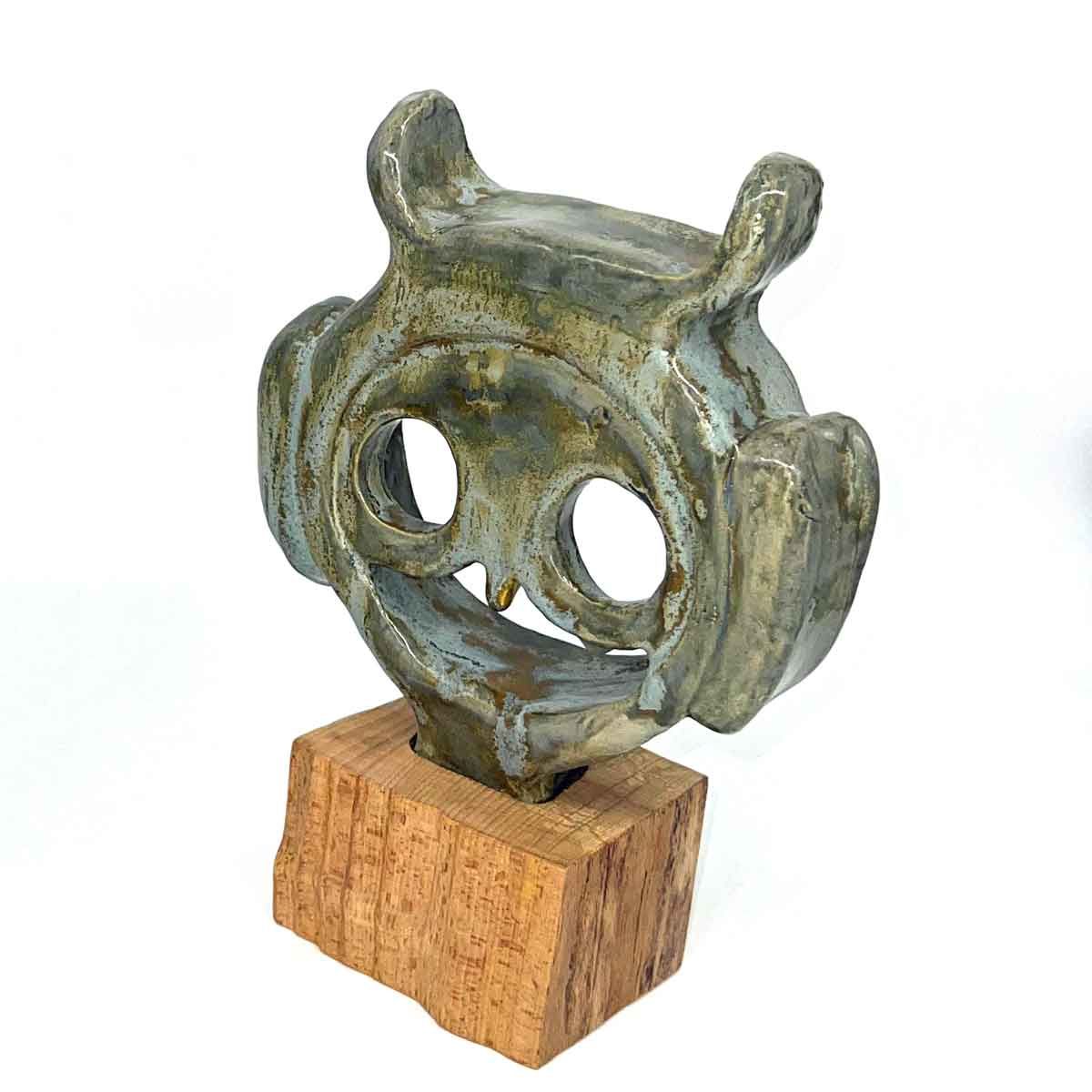 Kleine abstracte bronzen sculptuur met twee cirkelvormige openingen op een houten sokkel.