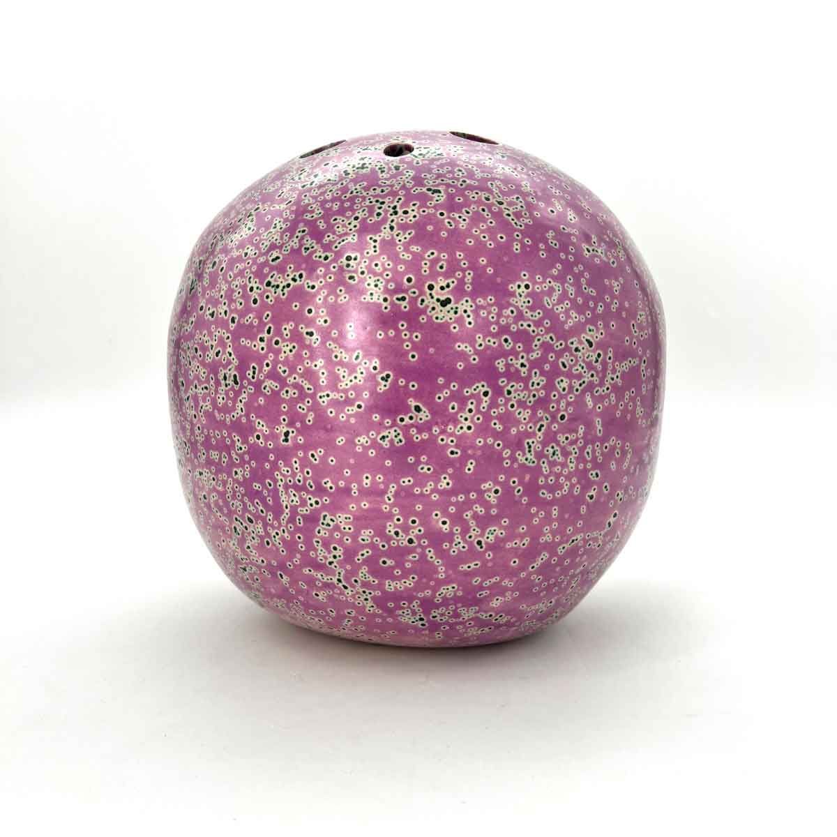 Roze, glinsterend, keramisch appelvormig ornament met een klein gaatje aan de bovenkant, op een witte achtergrond.