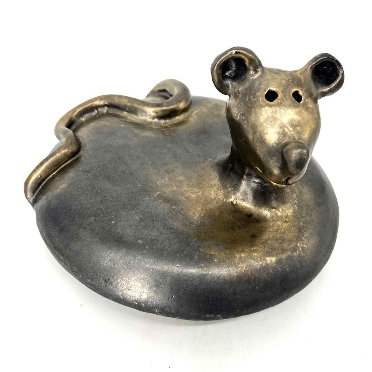 Metalen muisvormig sieraad met een grijs lijfje en een messingkleurige kop op een witte achtergrond.