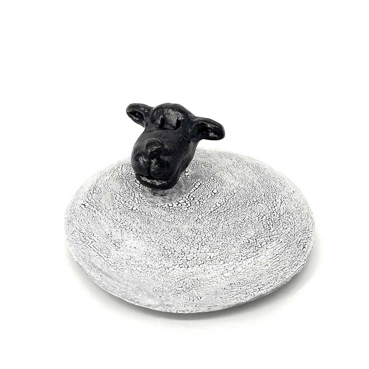 Klein zwart schaapje beeldje op een gespikkelde grijze ovale voet.