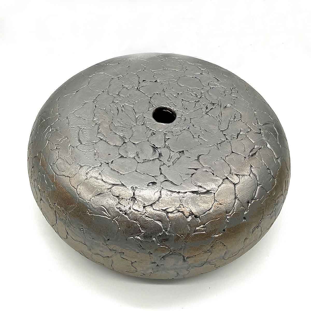 Rond, grijs metalen gewicht met een klein gaatje in het midden.