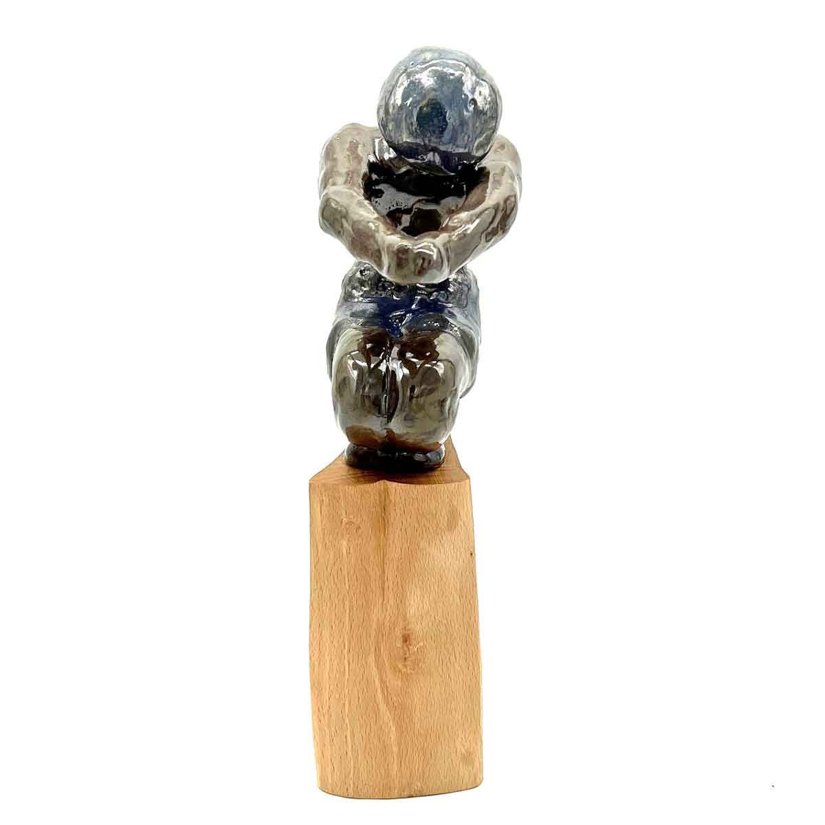 Kleine abstracte sculptuur bestaande uit gestapelde, glanzende, steenachtige vormen op een houten sokkel.