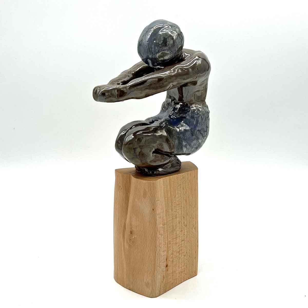 Klein abstract metalen beeldje op een houten sokkel, in donkerblauwe en zilverkleurige tinten.